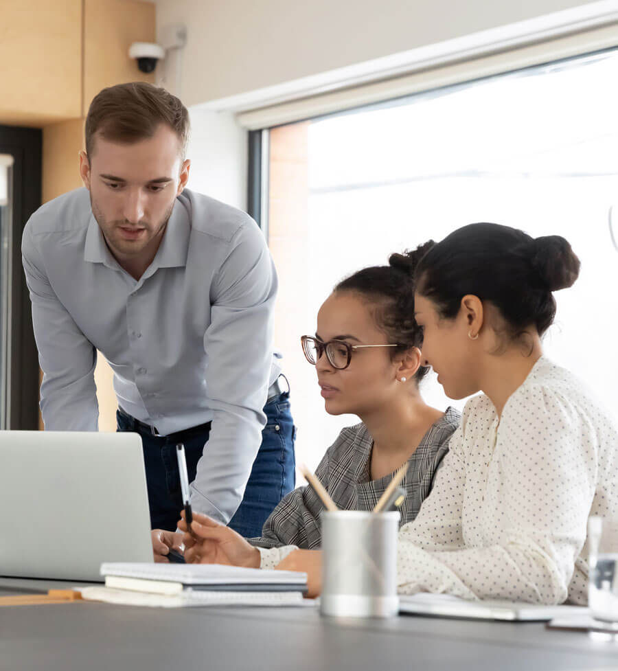 Three people in an office looking at a laptop